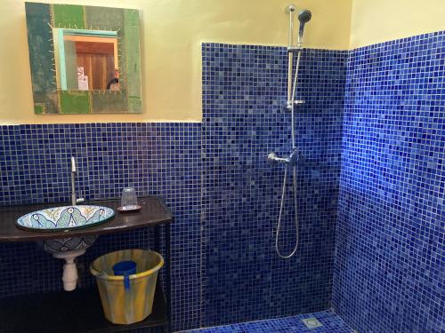 a blue tiled bathroom with a shower and a sink at Villa Rose in Bobo-Dioulasso