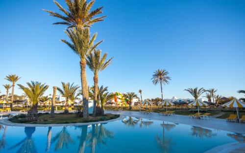 a pool with palm trees and umbrellas at a resort at Djerba Holiday Beach in Midoun