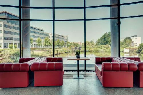 a room with red couches and a table and windows at Amedia Amsterdam Airport Schiphol, Trademark Collection by Wyndham in Schiphol