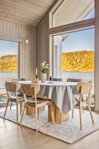 a dining room with a table and chairs and windows at Beachfront Paradise Lofoten in Bøstad