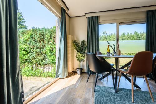 une salle à manger avec une table, des chaises et une grande fenêtre dans l'établissement Chalet met eigen tuin aan de Veluwse bosrand, à Putten