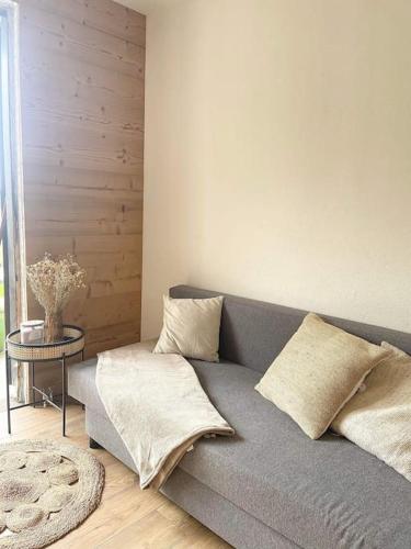 een woonkamer met een grijze bank en een tafel bij Appartement cosy in Métabief