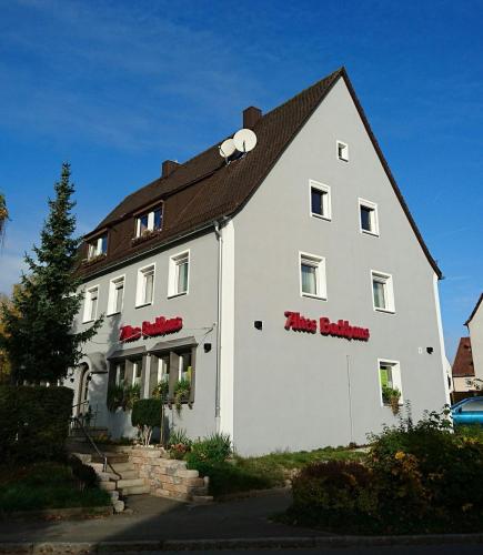 a large white building with red signs on it at Pension Altes Backhaus in Herzogenaurach
