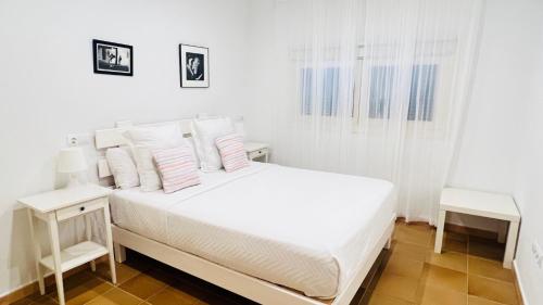 una camera da letto bianca con un letto bianco con cuscini bianchi di Casa Nena Es Calo a Es Caló de Sant Agustí
