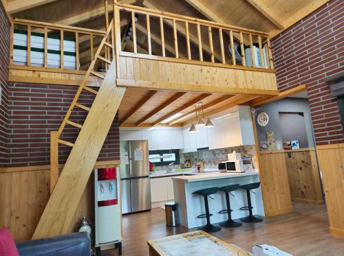 a large kitchen with a wooden staircase in a house at Sodamhyang Pension in Jeju