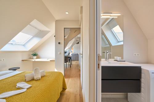 a bedroom with a yellow bed and a bathroom with skylights at Place du Grand Sablon in Brussels