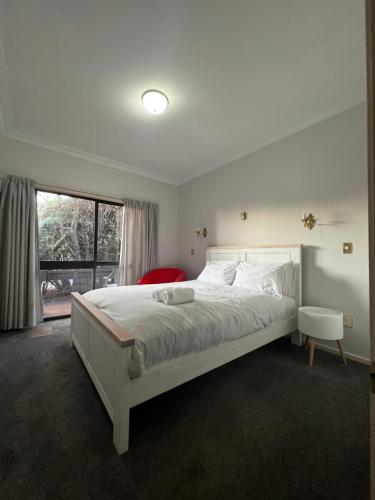 a bedroom with a large white bed and a window at Young Woods Lodge in Rotorua