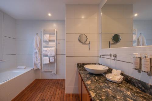 a white bathroom with a sink and a tub and a sink at Hôtel de la Plage in Plonévez-Porzay