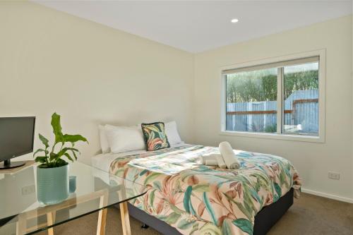 a bedroom with a bed and a desk and a window at Cosy and Central in Taupo