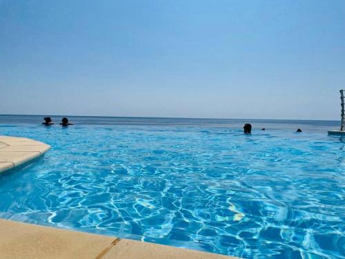 un groupe de personnes nageant dans une grande piscine bleue dans l'établissement Appart vue mer avec piscine chauffée, à Saint-Raphaël