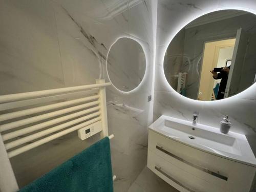 a white bathroom with a sink and a mirror at Appart vue mer avec piscine in Saint-Raphaël