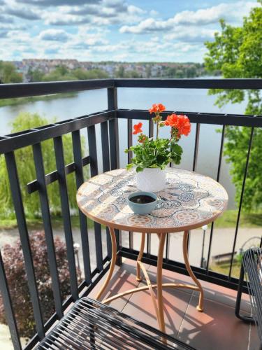 a table with flowers on top of a balcony at Przystań 21 - Lake View Apartament, bulwar, klimatyzacja, wanna, parking in Iława
