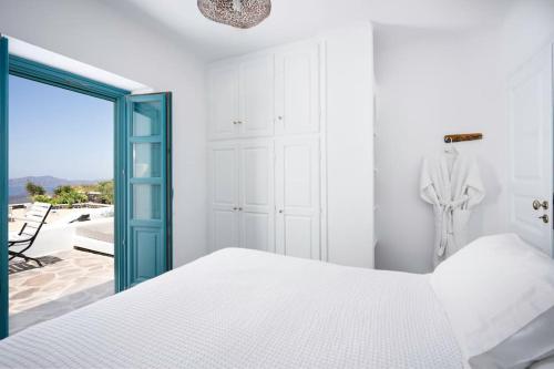 a bedroom with a white bed and a blue door at Villa Oinos - Sunset Views in Órmos Athiniós