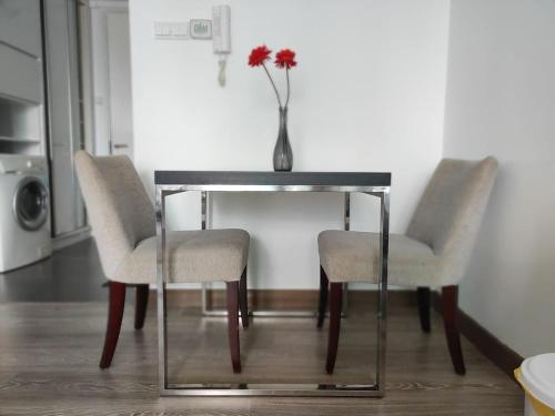 a table with two chairs and a vase with a flower on it at One Bukit Ceylon KLCC in Kuala Lumpur