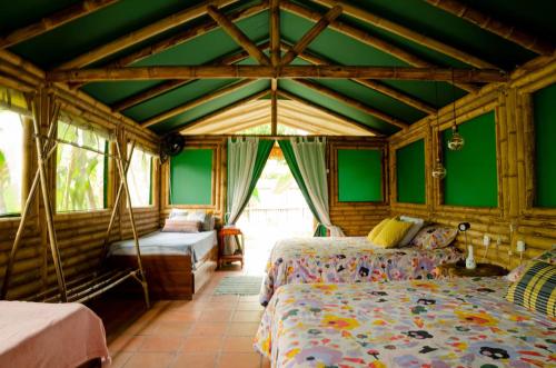 a bedroom with two beds in a room with green walls at Aguas Claras Bamboo Glamping in Guaduas