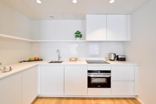a white kitchen with white cabinets and a sink at Place du Grand Sablon in Brussels