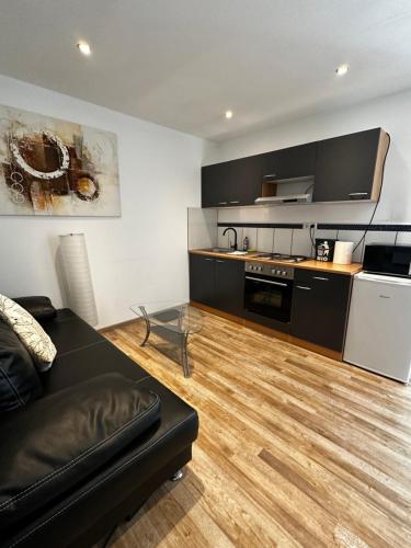 uma sala de estar com um sofá preto e uma cozinha em Heidelberg Apartments em Heidelberg