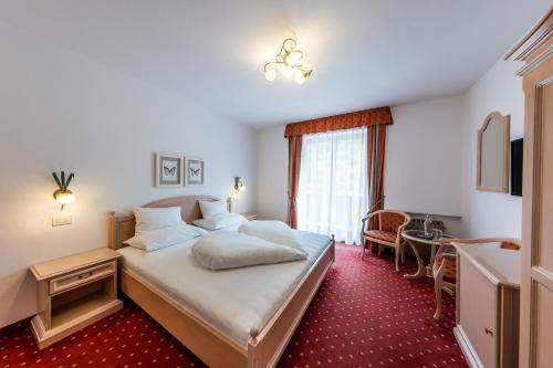 カンポ・トゥーレスにあるGarni Zimmerhoferのベッドとデスクが備わるホテルルームです。