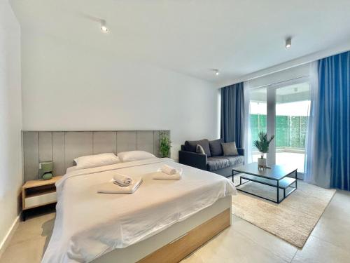 - une chambre avec un grand lit blanc et un canapé dans l'établissement Horizon Residences Andjela, à Budva