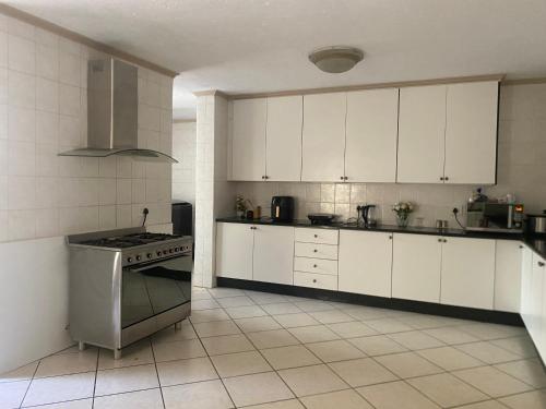 a kitchen with white cabinets and a stove top oven at Siena Sun Guesthouse Rooms and Breakfast Option in Midrand