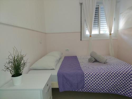 een slaapkamer met een bed met paarse lakens en een raam bij magical apartment close to the Baha'i Gardens in Haifa