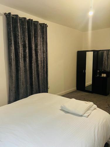 1 dormitorio con cama blanca y cortina negra en The Pleasant House en Mánchester