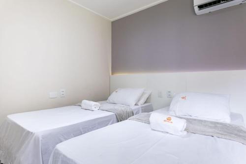 three beds in a room with white sheets and towels at Flat ou Bangalo Luxo Beach Class Beira Mar Muro Alto in Porto De Galinhas