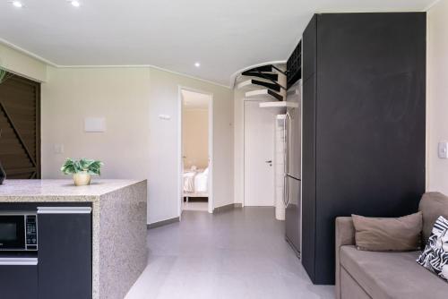 a kitchen and living room with a counter and a couch at Flat ou Bangalo Luxo Beach Class Beira Mar Muro Alto in Porto De Galinhas