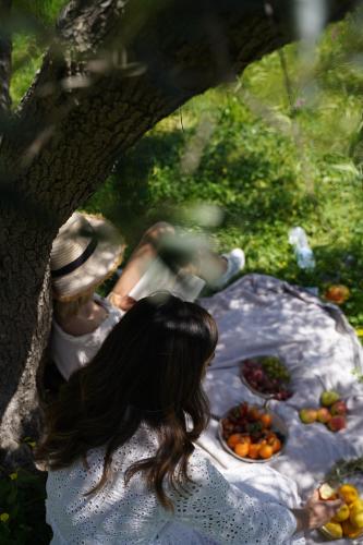 a woman sitting under a tree with fruit on a table at Stella in the Village Studio Sea View in Plakias