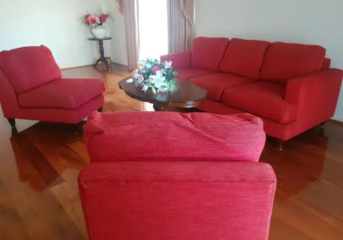 a living room with two red couches and a table at Roxy - A Spacious Cosy Getaway - Near Mel Airport in Craigieburn