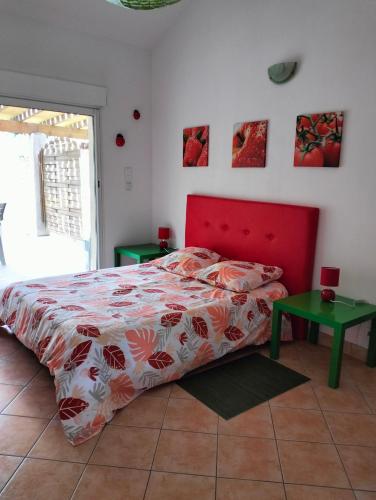 une chambre avec un lit rouge et une table verte dans l'établissement Petit Mazet Fruits rouges, à Eyragues