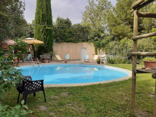 een zwembad in een tuin met een zwarte stoel bij Petit Mazet Fruits rouges in Eyragues