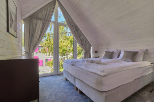 1 dormitorio con cama grande y ventana grande en Domki Premium Nautica blisko plaży, en Rewal