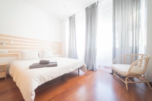 フェロルにあるApartamento Tierraのベッドと椅子のある白い寝室