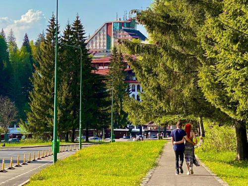 a man and a woman walking down a sidewalk at Hotel Piatra Mare in Poiana Brasov