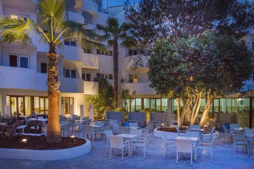 a hotel with tables and chairs in front of a building at Sentido Fido Tucan - Adults Only in Cala d´Or