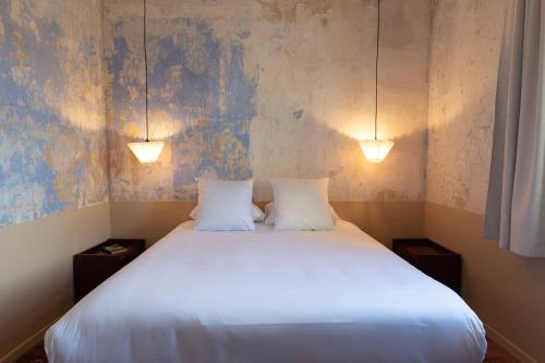 a bedroom with a large white bed with two lamps at Hôtel La Prison in Béziers