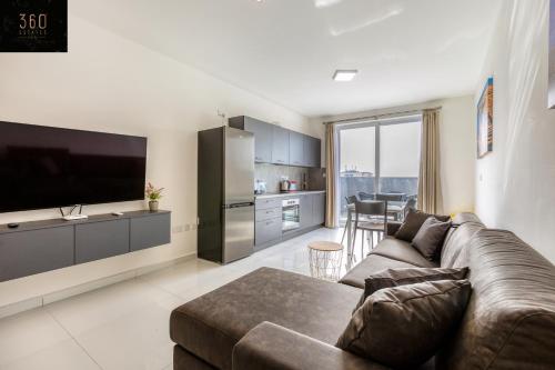 un soggiorno con divano marrone e una cucina di A sunny 2BR Pent with comfy, fully equipped living by 360 Estates a San Pawl il-Baħar