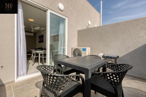 un tavolo nero e sedie sul balcone di A sunny 2BR Pent with comfy, fully equipped living by 360 Estates a San Pawl il-Baħar
