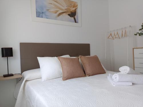 a white bed with brown and white pillows on it at APARTAMENTOS MATUTE in Almodóvar del Río