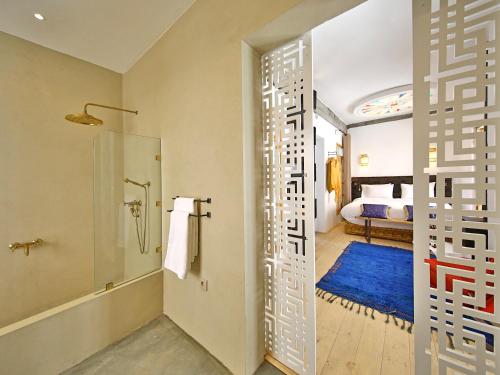 a bathroom with a shower and a glass door with a bed at Riad EspritBleu in Essaouira