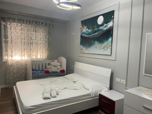 een witte slaapkamer met een bed en een teddybeer bij Premium Apartaments 10 in Vlorë