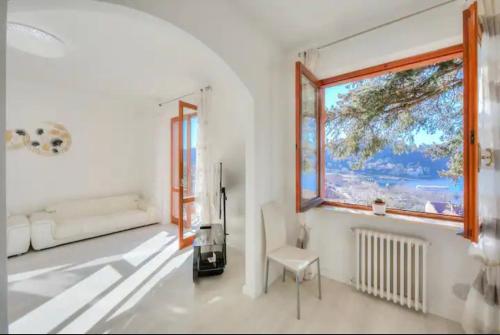 a white room with a window and a chair at Apartment With View Lake Maggiore/Laveno Mombello in Laveno