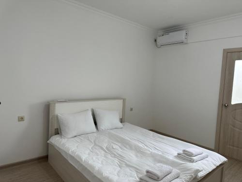 1 dormitorio con 1 cama blanca y 2 toallas en Апартаменты Esnat en Gudautʼa