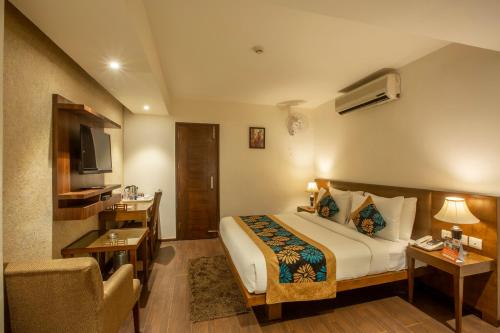 um quarto de hotel com uma cama e uma televisão em Hotel Arch Plaza - Near Delhi Airport em Nova Deli