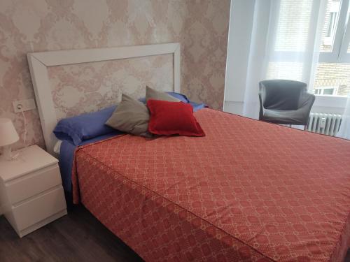 um quarto com uma cama vermelha com almofadas em Bnap Gesta em Oviedo