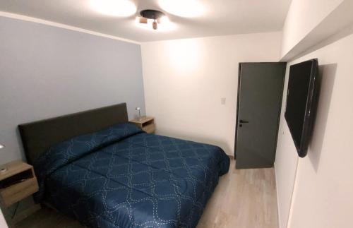 Un dormitorio con una cama azul y un televisor. en Nice Full Apartment Downtown Salta, en Salta