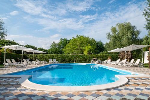 a large swimming pool with chairs and umbrellas at B&B Villa Corte Degli Dei in Lucca
