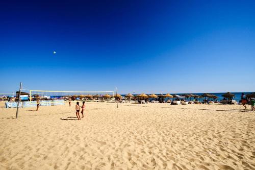 a group of people playing volleyball on a beach at 2-Bedroom Beachside Apartment with Pool & Parking in Quarteira