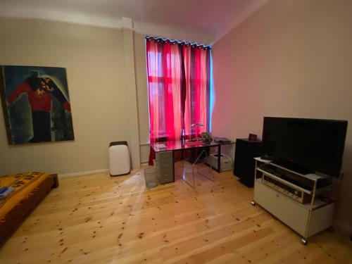 a living room with a television and a red curtain at FeWo Grüne Mommsenstraße - bei Becker klingeln in Berlin